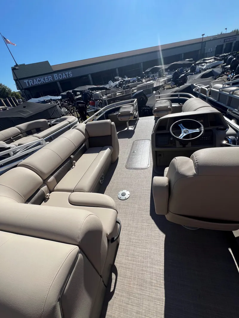 Slide: The Image of 2025 Sun Tracker Fishin' Barge 22 XP3 interior with beige seating and steering console. - 4