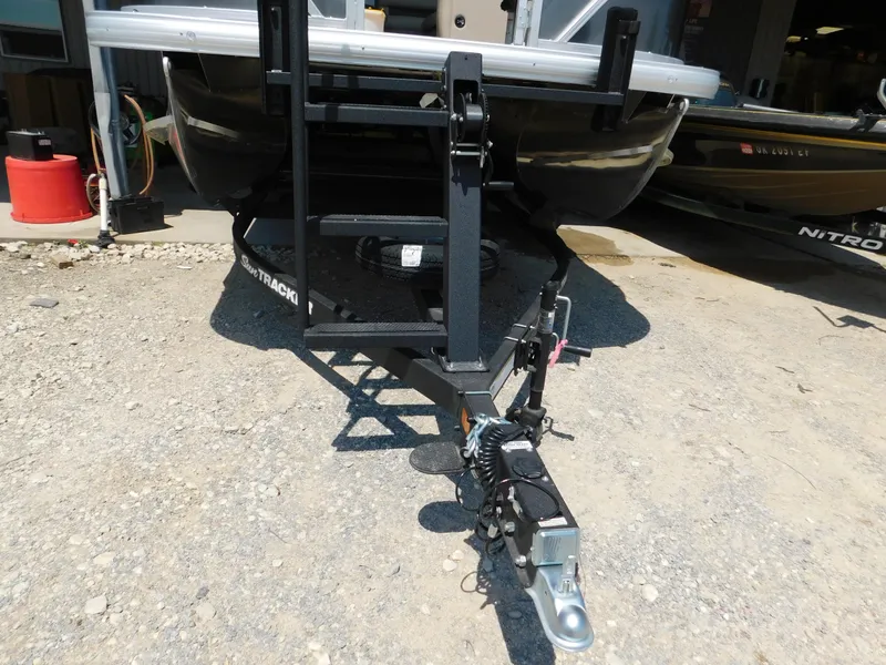 Slide: The Image of 2025 Sun Tracker Fishin' Barge 22 DLX trailer hitch on gravel surface. - 28