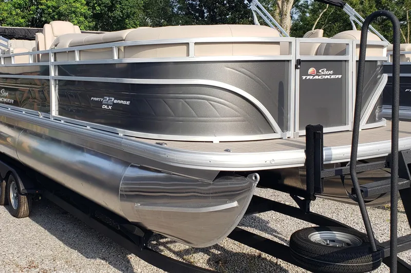 The Image of 2025 Sun Tracker Party Barge 22 DLX pontoon boat on trailer, parked outdoors. - 0