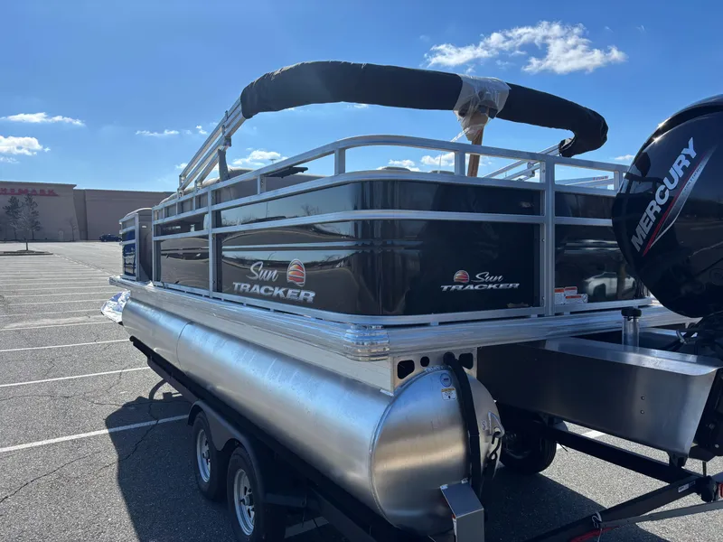 Slide: The Image of 2025 Sun Tracker SportFish 22 DLX pontoon boat in parking lot, featuring Mercury engine. - 2
