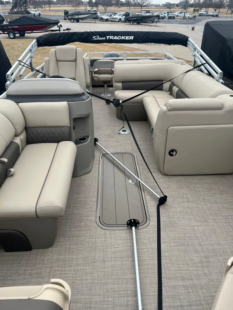 Slide: The Image of 2025 Sun Tracker Fishin' Barge 22 XP3 interior with beige seating and spacious layout. - 2