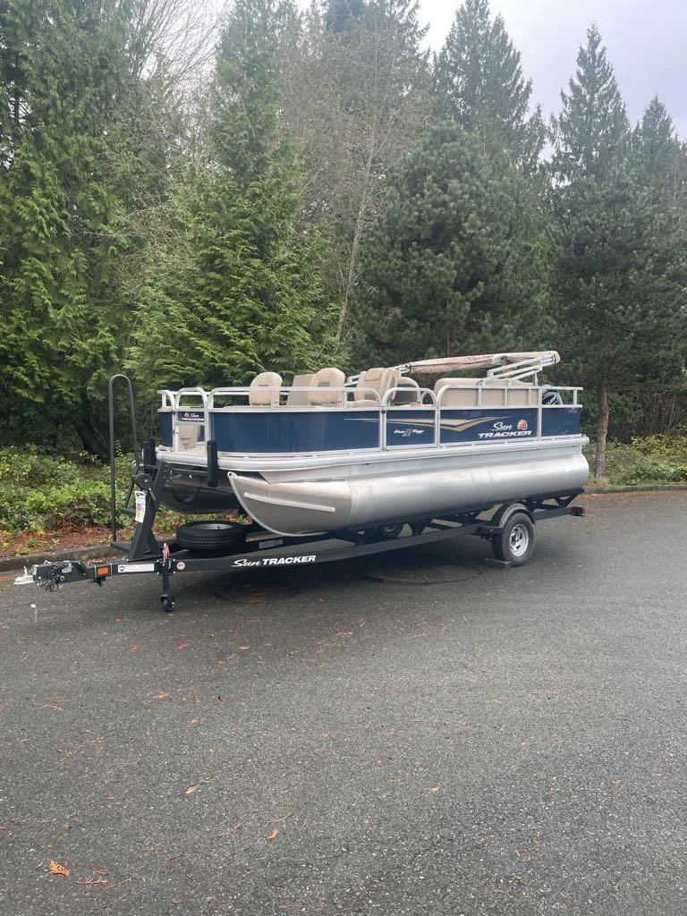 The Image of 2025 Sun Tracker Bass Buggy 18 DLX pontoon boat on trailer, parked outdoors. - 0