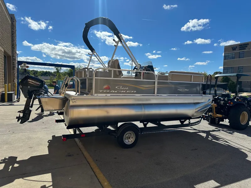 Slide: The Image of 2025 Sun Tracker Party Barge 16 DLX pontoon boat on trailer, sunny day. - 2