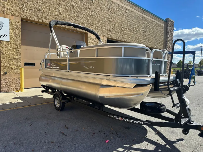Slide: The Image of 2025 Sun Tracker Party Barge 16 DLX pontoon boat on trailer, parked outdoors. - 3