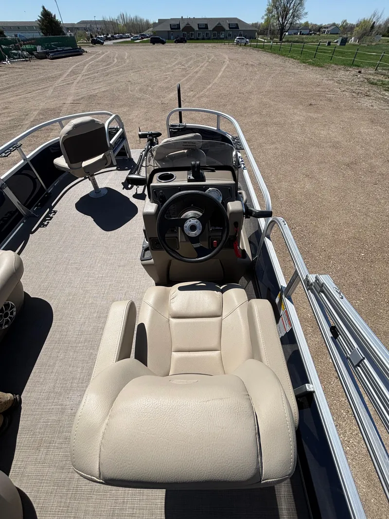 Slide: The Image of 2025 Sun Tracker Bass Buggy 16 XL Select pontoon boat interior with beige seating and steering console. - 5