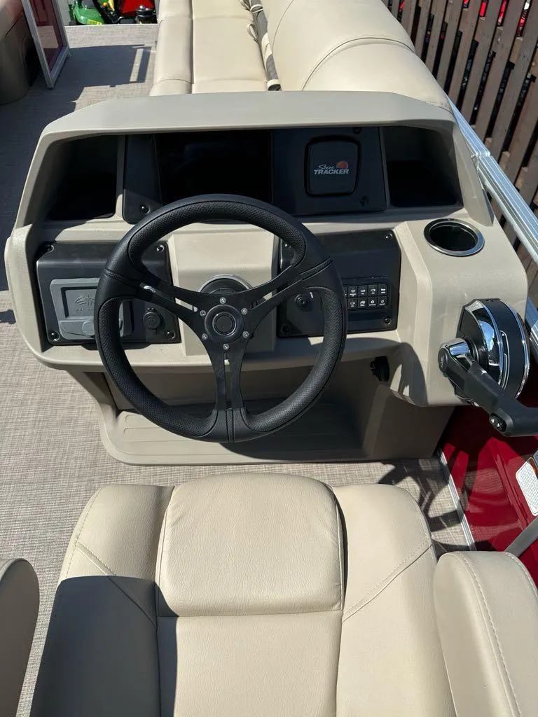 Slide: The Image of 2025 Sun Tracker Party Barge 24 DLX steering console with beige seating and controls. - 3