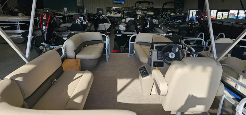 Slide: The Image of 2025 Sun Tracker Party Barge 16 DLX interior with beige seating and steering console. - 2