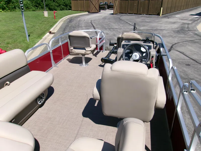 Slide: The Image of 2025 Sun Tracker Bass Buggy 18 DLX pontoon boat interior with beige seating and steering console. - 4