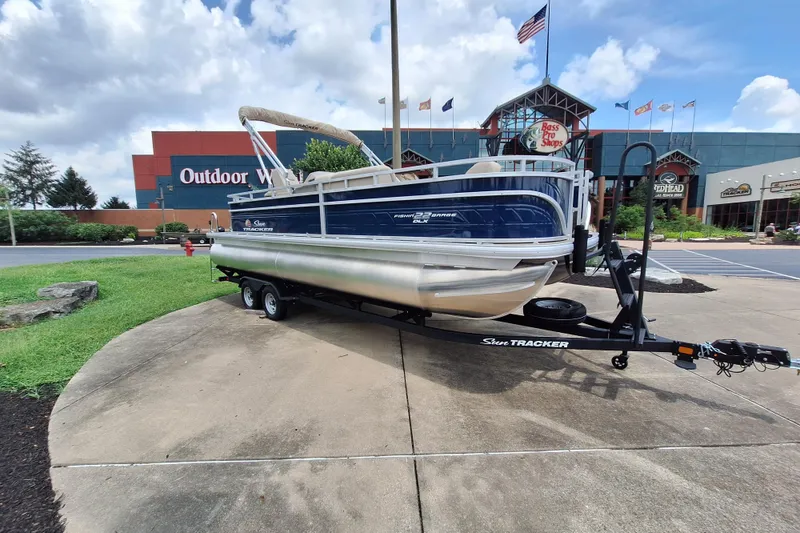 Slide: The Image of 2025 Sun Tracker Fishin' Barge 22 DLX pontoon boat on trailer outside Bass Pro Shops. - 4