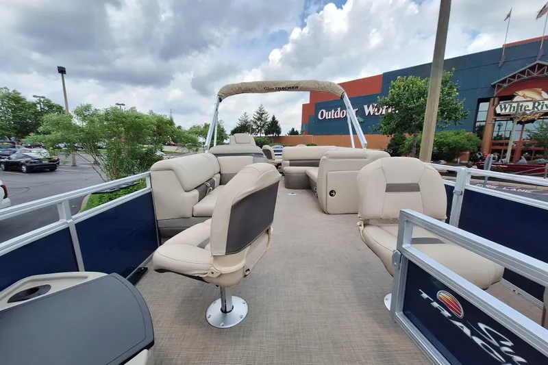 Slide: The Image of 2025 Sun Tracker Fishin' Barge 22 DLX pontoon boat with beige seating, parked outdoors. - 8
