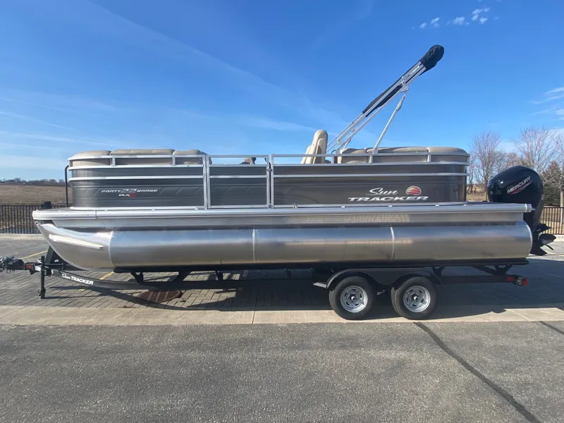 The Image of 2025 Sun Tracker Party Barge 22 XP3 pontoon boat on trailer, parked outdoors. - 0