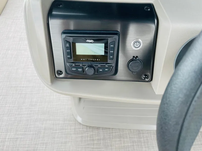 Slide: The Image of 2025 Sun Tracker Party Barge 18 DLX dashboard with audio controls and power button. - 22