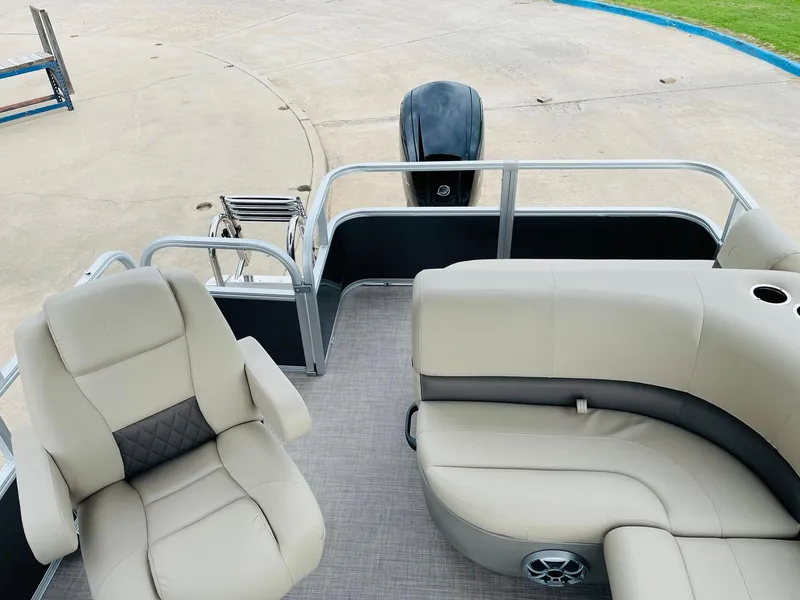 Slide: The Image of 2025 Sun Tracker Party Barge 18 DLX interior with beige seating and outboard motor. - 26
