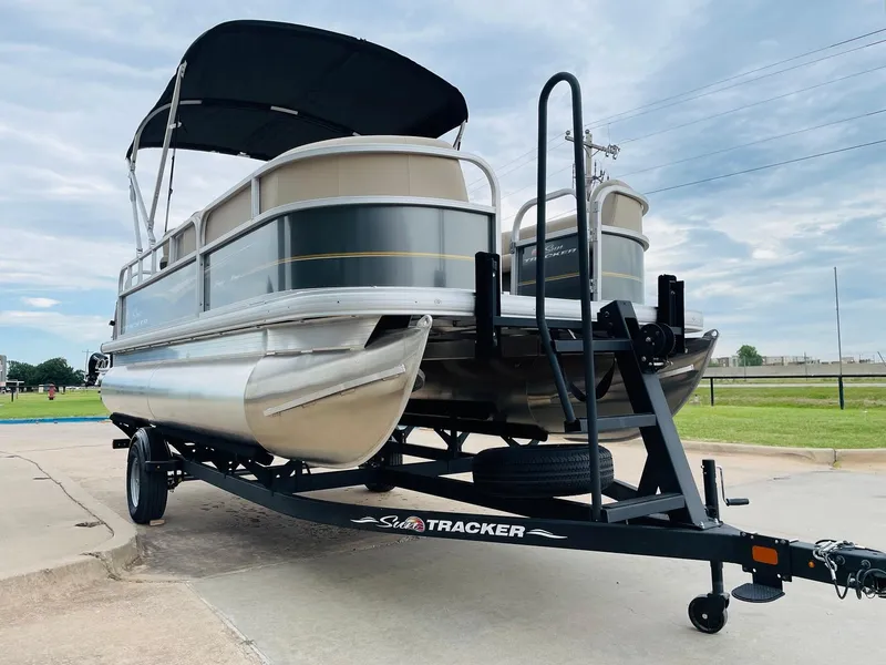 Slide: The Image of 2025 Sun Tracker Party Barge 18 DLX pontoon boat on trailer, outdoor setting. - 3