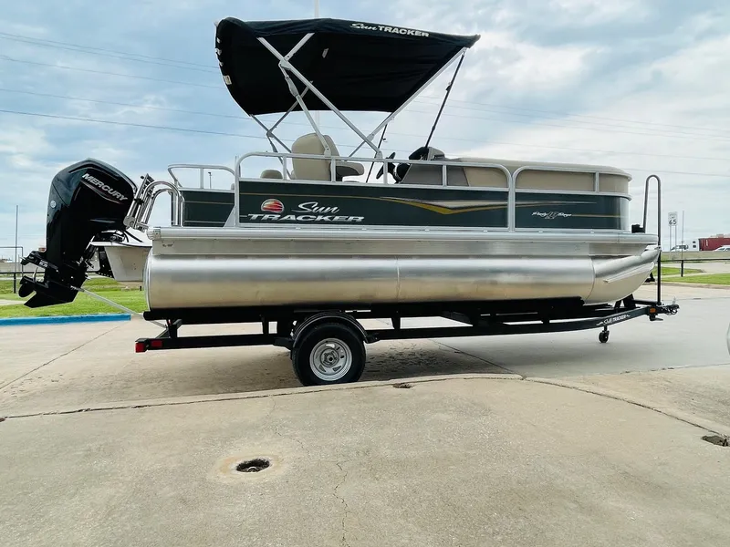 Slide: The Image of 2025 Sun Tracker Party Barge 18 DLX pontoon boat on trailer, outdoor view. - 4