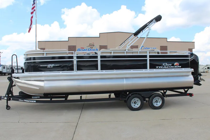 The Image of 2025 Sun Tracker SportFish 22 DLX pontoon boat on trailer at dealership. - 0
