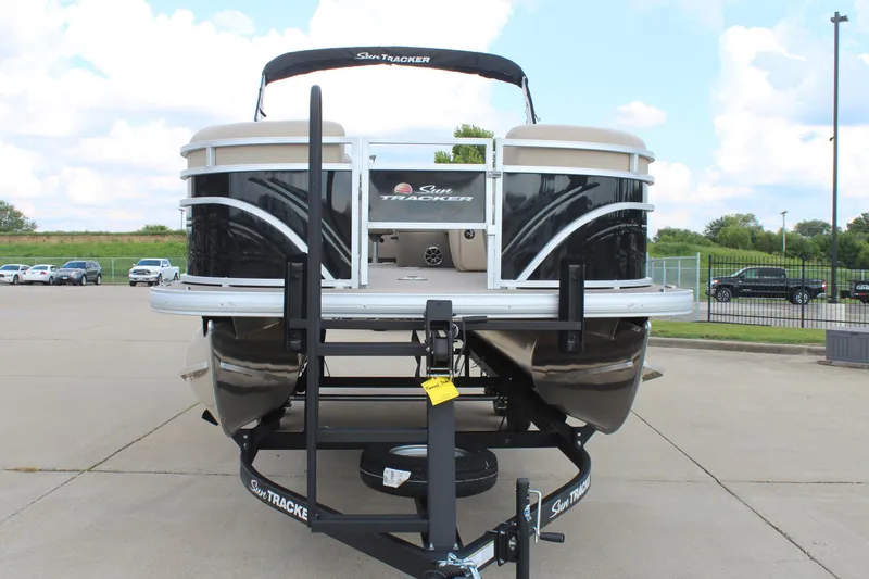 Slide: The Image of 2025 Sun Tracker SportFish 22 DLX pontoon boat on trailer, parked outdoors. - 2