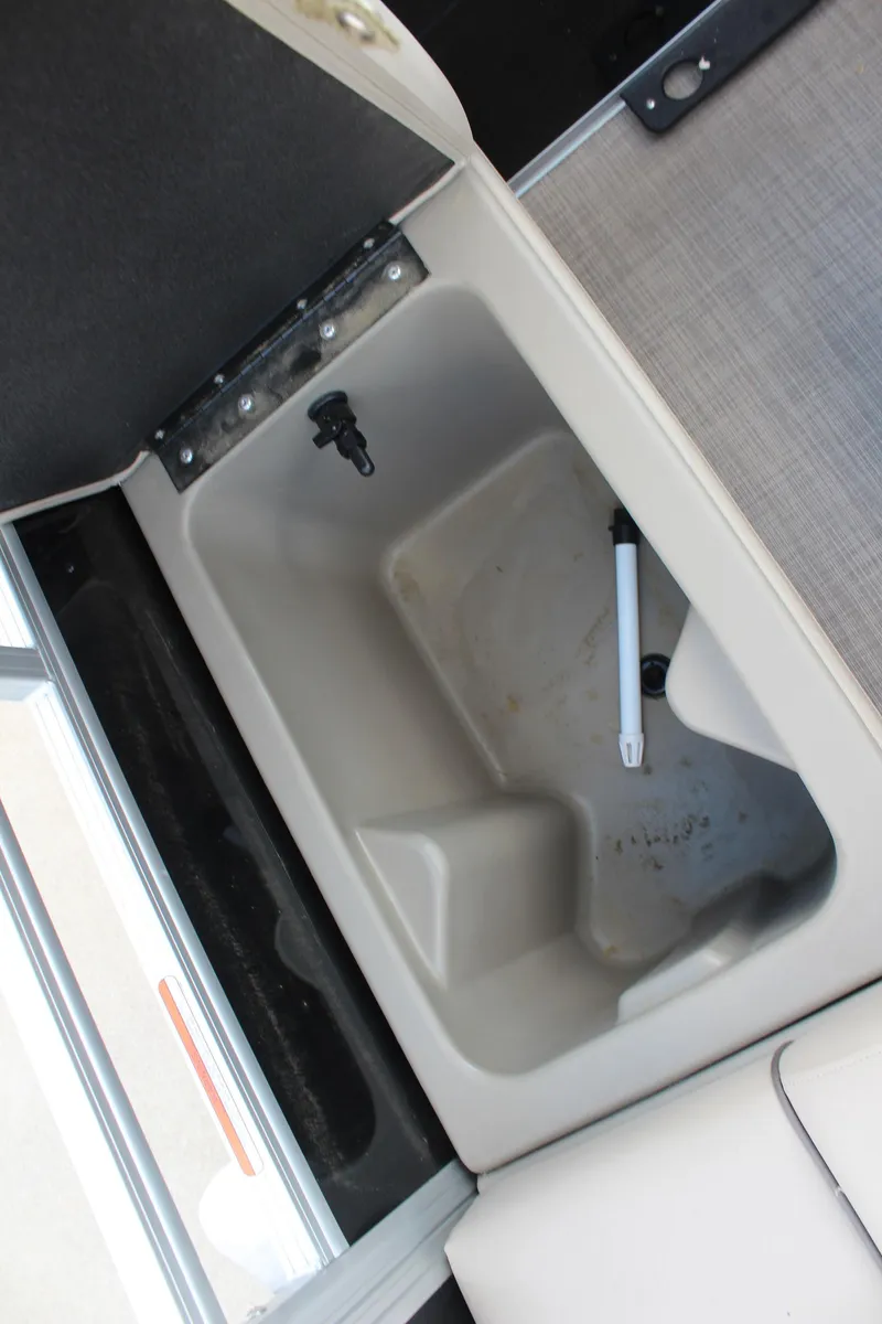 Slide: The Image of 2025 Sun Tracker SportFish 22 DLX storage compartment with open lid and drain plug. - 21