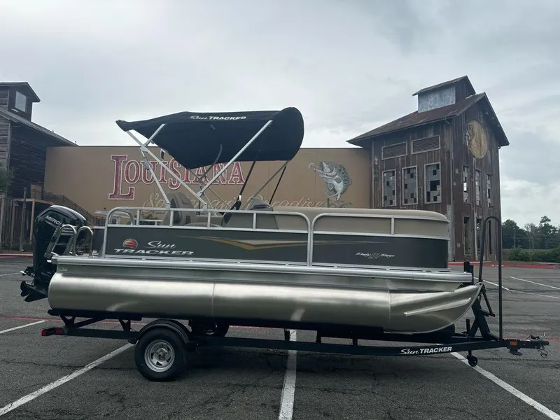 Slide: The Image of 2025 Sun Tracker Party Barge 18 DLX pontoon boat on trailer in parking lot. - 2
