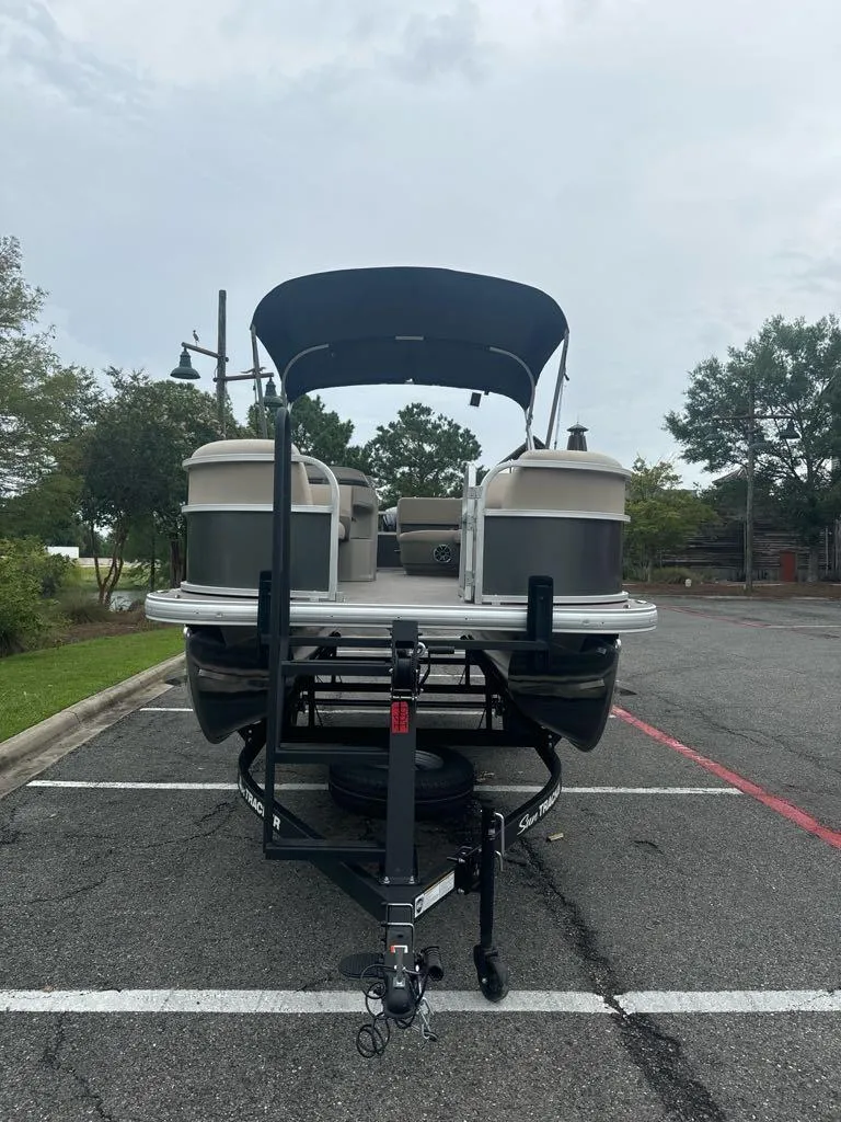 Slide: The Image of 2025 Sun Tracker Party Barge 18 DLX pontoon boat on trailer in parking lot. - 3