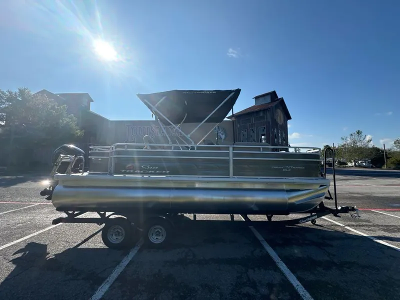 Slide: The Image of 2025 Sun Tracker Fishin' Barge 20 DLX pontoon boat in parking lot, sunny day. - 2