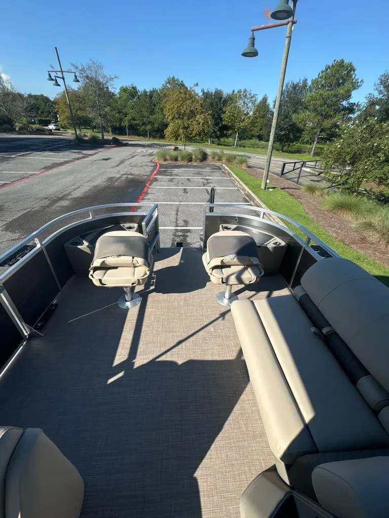Slide: The Image of 2025 Sun Tracker Fishin' Barge 20 DLX pontoon boat with seating, parked outdoors. - 6