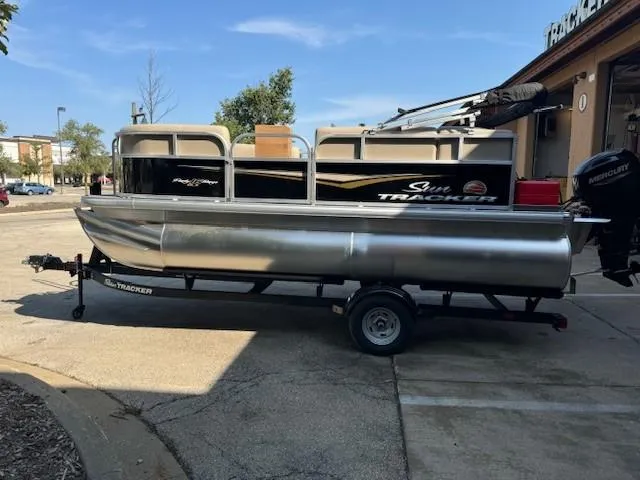 Slide: The Image of 2025 Sun Tracker Party Barge 16 DLX pontoon boat on trailer in parking lot. - 5