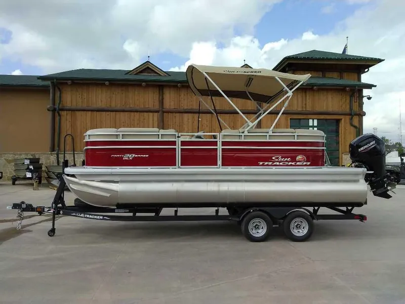 The Image of 2025 Sun Tracker Party Barge 20 DLX pontoon boat on trailer, parked outdoors. - 0