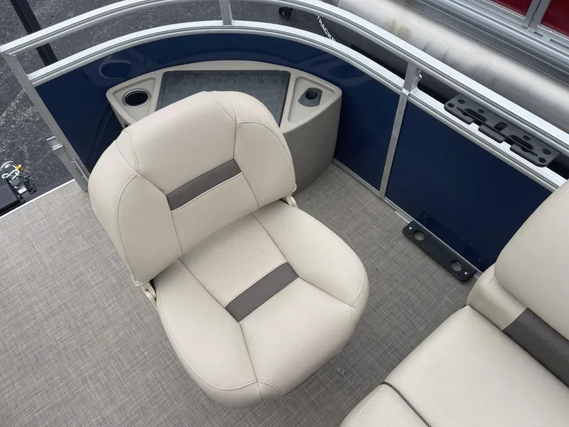 Slide: The Image of 2025 Sun Tracker Fishin' Barge 20 DLX interior with beige seating and blue paneling. - 13