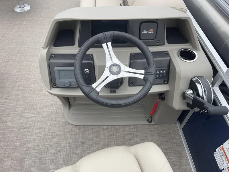 Slide: The Image of 2025 Sun Tracker Fishin' Barge 20 DLX steering console with modern controls and beige upholstery. - 15
