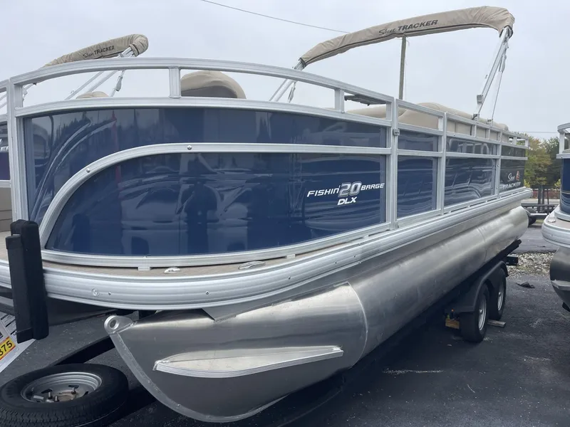 Slide: The Image of 2025 Sun Tracker Fishin' Barge 20 DLX pontoon boat, blue exterior, on trailer. - 2
