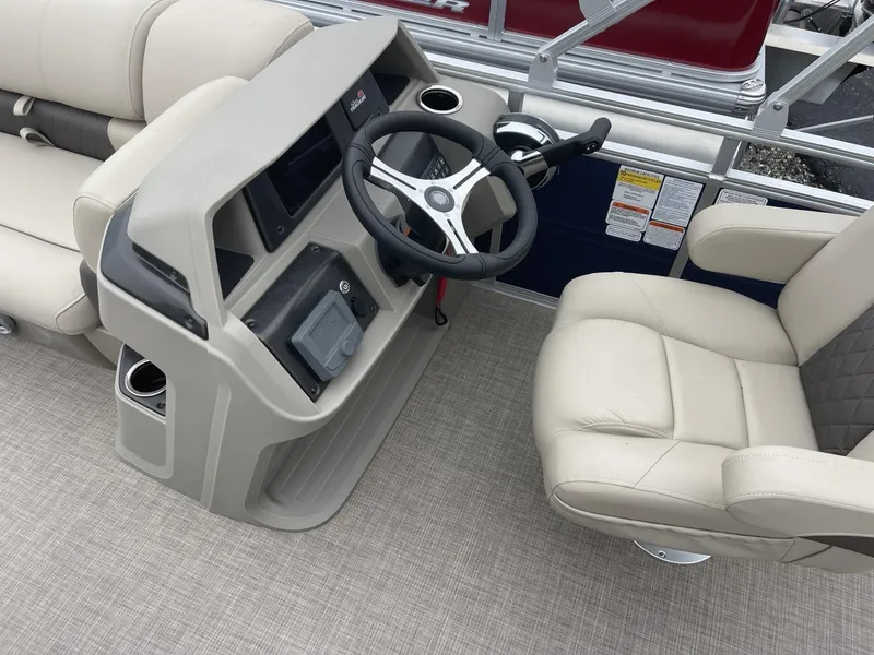 Slide: The Image of 2025 Sun Tracker Fishin' Barge 20 DLX helm with beige seating and steering wheel. - 9