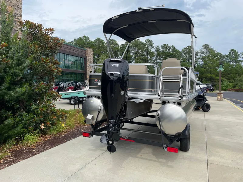 Slide: The Image of 2025 Sun Tracker Party Barge 18 DLX pontoon boat with Mercury 75 engine, parked outdoors. - 3