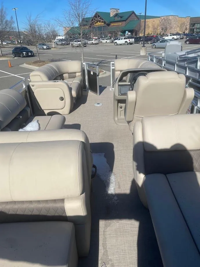 Slide: The Image of 2025 Sun Tracker Party Barge 22 RF DLX with beige seating in a parking lot. - 2