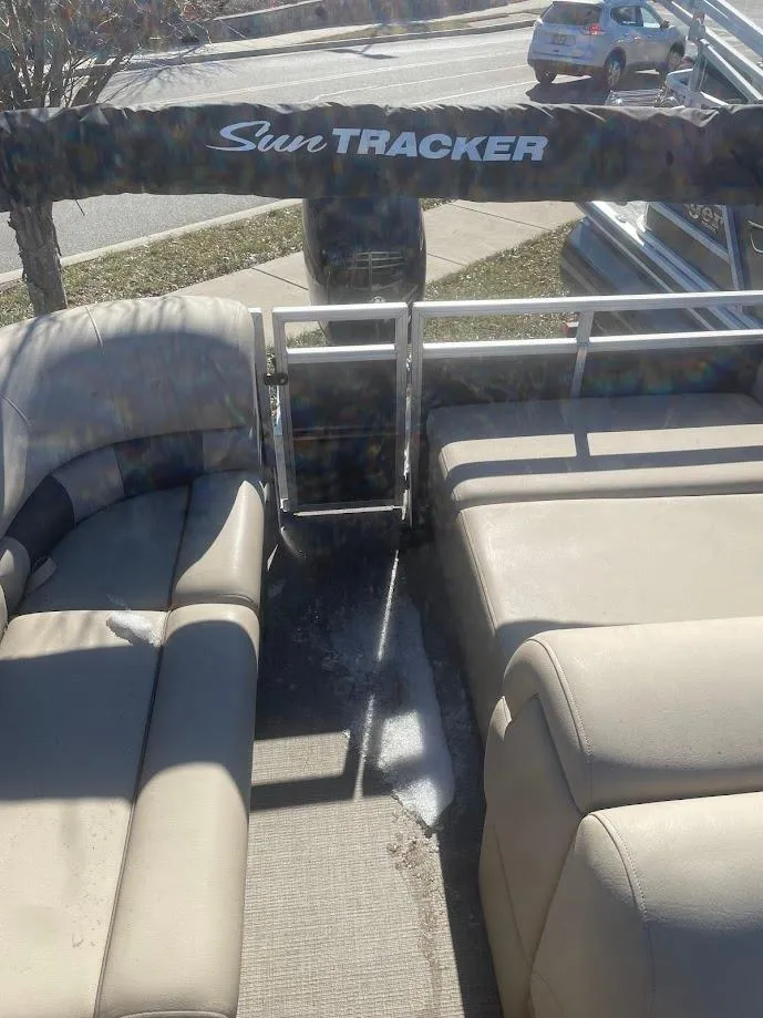 Slide: The Image of 2025 Sun Tracker Party Barge 22 RF DLX with beige seating, parked outdoors. - 3