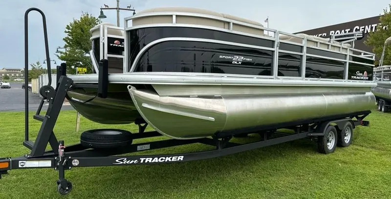 Slide: The Image of 2025 Sun Tracker SportFish 22 DLX pontoon boat on trailer, parked on grass. - 2