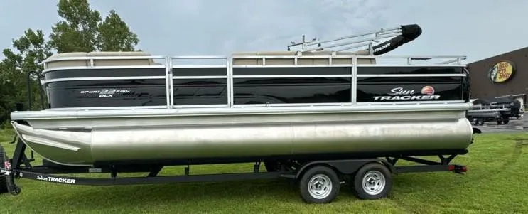 Slide: The Image of 2025 Sun Tracker SportFish 22 DLX pontoon boat on trailer, parked on grass. - 3