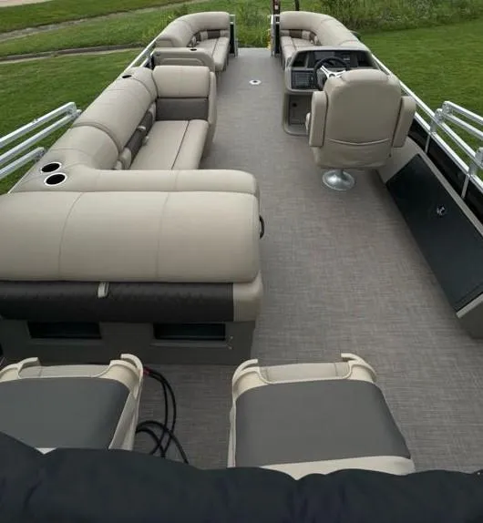 Slide: The Image of 2025 Sun Tracker SportFish 22 DLX pontoon boat interior with plush seating and steering console. - 6