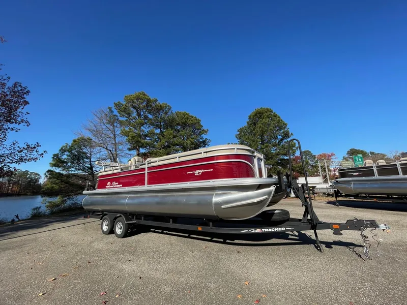 The Image of 2025 Sun Tracker Party Barge 24 DLX pontoon boat on trailer, parked outdoors. - 0