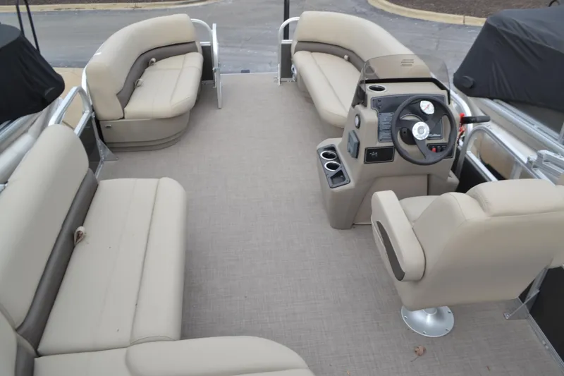 Slide: The Image of 2025 Sun Tracker Party Barge 16 DLX interior with beige seating and steering console. - 3