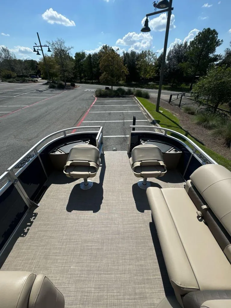 Slide: The Image of 2025 Sun Tracker Fishin' Barge 20 DLX pontoon boat with seating, parked outdoors. - 4