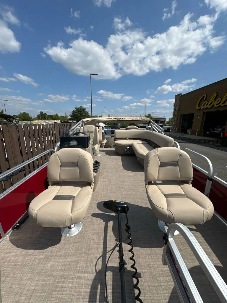 Slide: The Image of 2025 Sun Tracker Bass Buggy 18 DLX pontoon boat with beige seating under a blue sky. - 2
