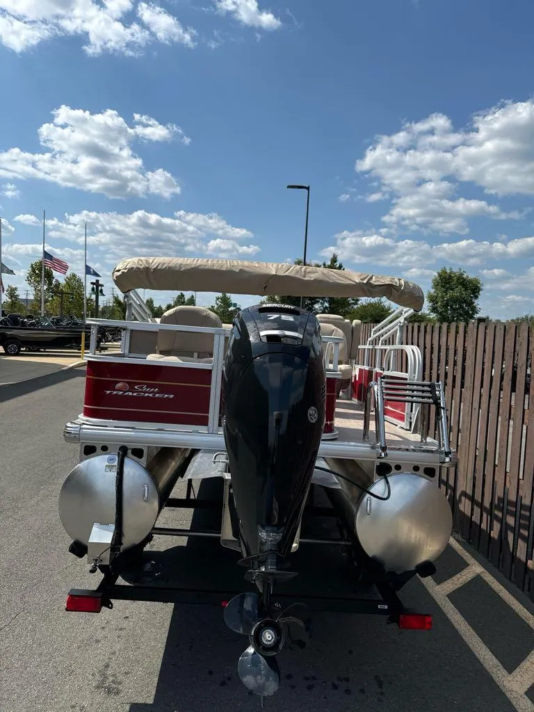 Slide: The Image of 2025 Sun Tracker Bass Buggy 18 DLX pontoon boat with outboard motor, parked outdoors. - 5