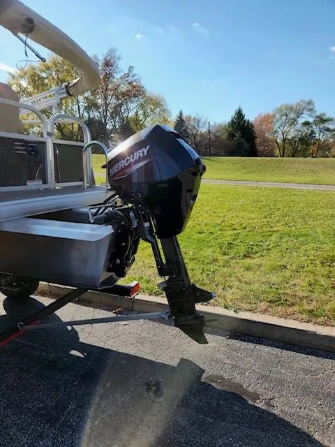 Slide: The Image of 2025 Sun Tracker Bass Buggy 16 XL Select with Mercury outboard motor in a sunny park setting. - 2