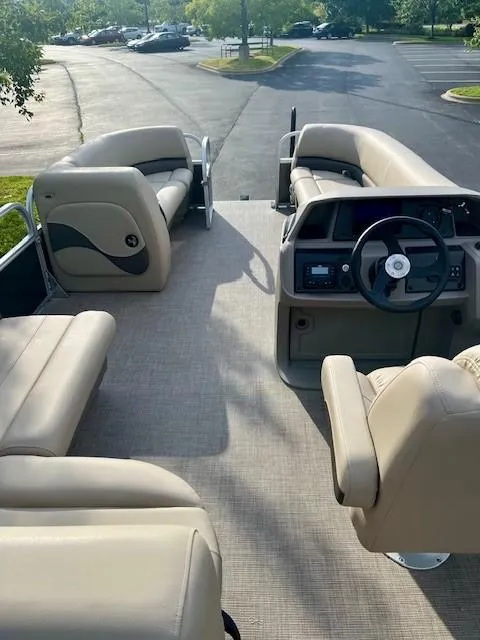 Slide: The Image of 2025 Sun Tracker Party Barge 18 DLX interior with beige seating and steering console. - 3