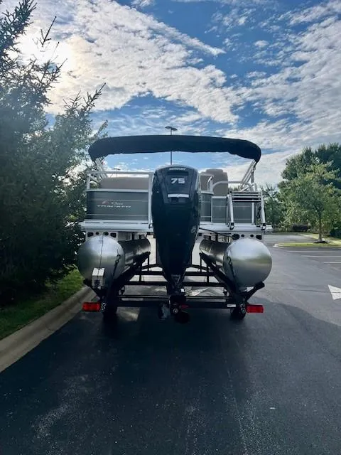 Slide: The Image of 2025 Sun Tracker Party Barge 18 DLX pontoon boat on a trailer, parked outdoors. - 5