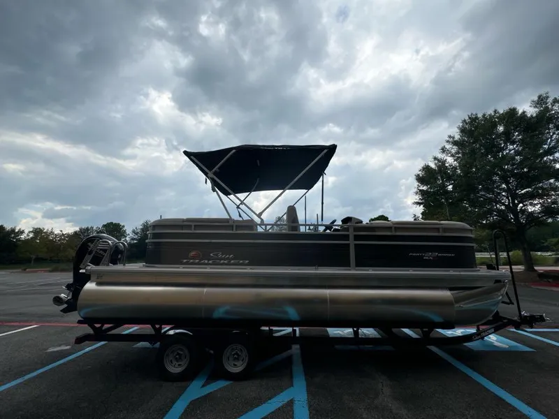 Slide: The Image of 2025 Sun Tracker Party Barge 22 RF XP3 pontoon boat on trailer, cloudy sky background. - 2