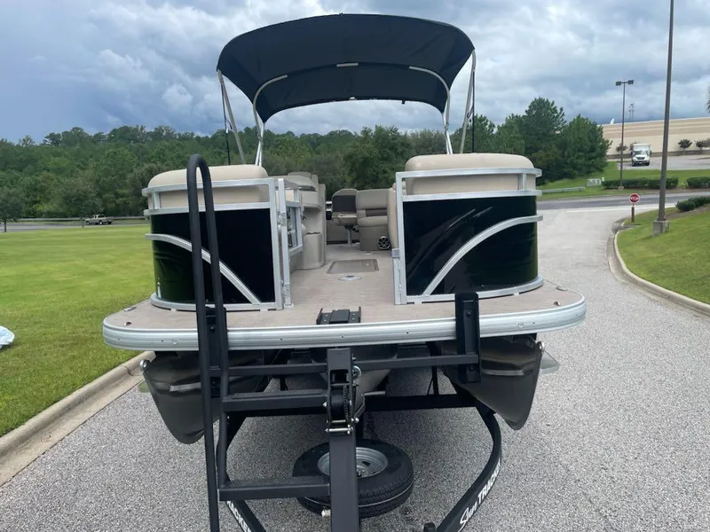 Slide: The Image of 2025 Sun Tracker SportFish 22 XP3 pontoon boat on trailer, parked outdoors. - 2