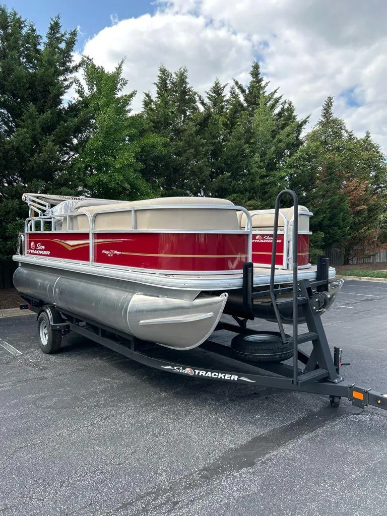 The Image of 2025 Sun Tracker Party Barge 18 DLX pontoon boat on trailer, parked outdoors. - 0