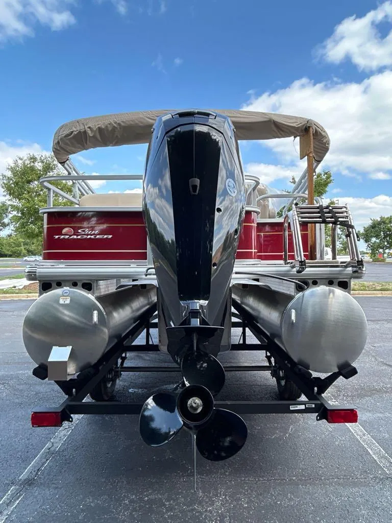 Slide: The Image of 2025 Sun Tracker Party Barge 18 DLX pontoon boat with outboard motor, parked on a trailer. - 3
